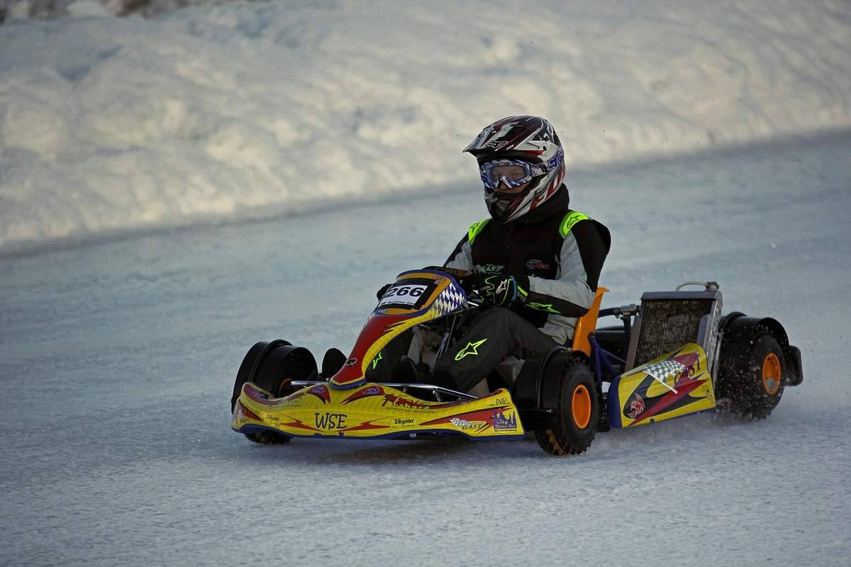 Pilote de karting jaune et rouge piloté sur piste mouillée en extérieur Pilote de karting jaune et rouge piloté sur piste mouillée en extérieur
