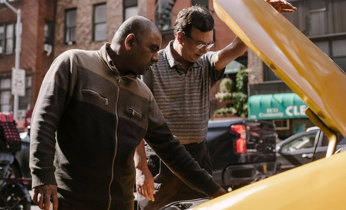 Deux hommes examinent le moteur d'une voiture jaune sur une rue Deux hommes examinent le moteur d'une voiture jaune sur une rue
