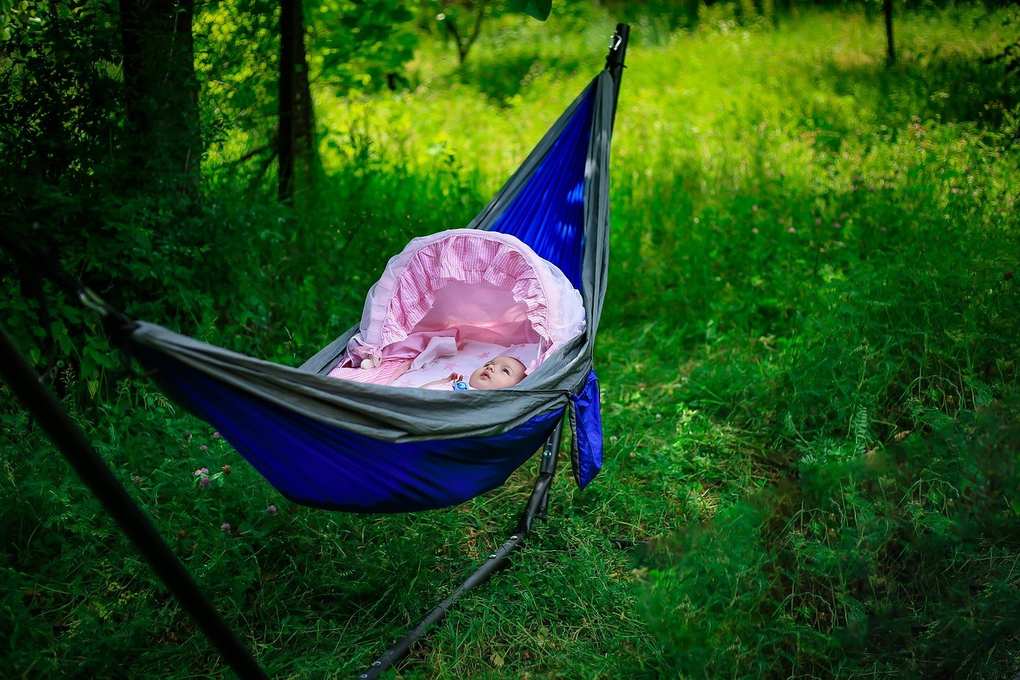 Hamac bleu avec tente bébé rose dans un champ herbeux Hamac bleu avec tente bébé rose dans un champ herbeux
