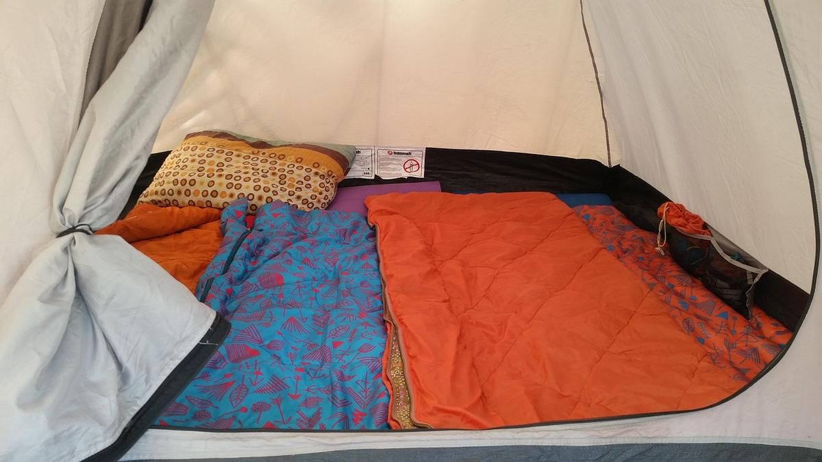 Tente avec draps colorés, coussins et sac de couchage, vue intérieure Tente avec draps colorés, coussins et sac de couchage, vue intérieure