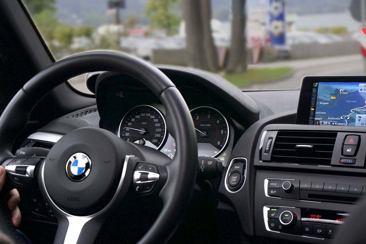Intérieur d'une BMW, main sur le volant, écran GPS allumé