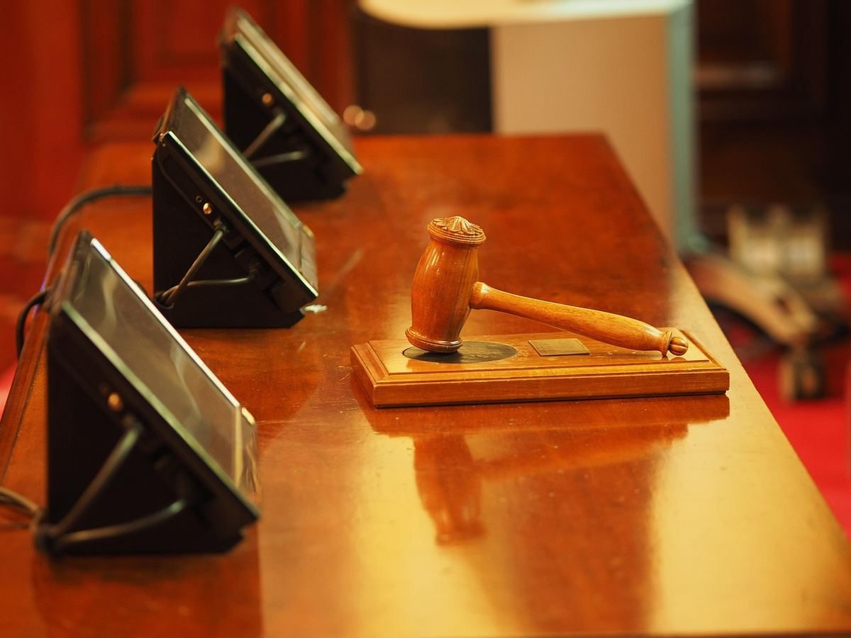Marteau de juge en bois sur un bureau avec microphones, dans une salle d'audience