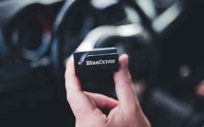 Une main tient un petit boîtier noir à l'intérieur d'une voiture