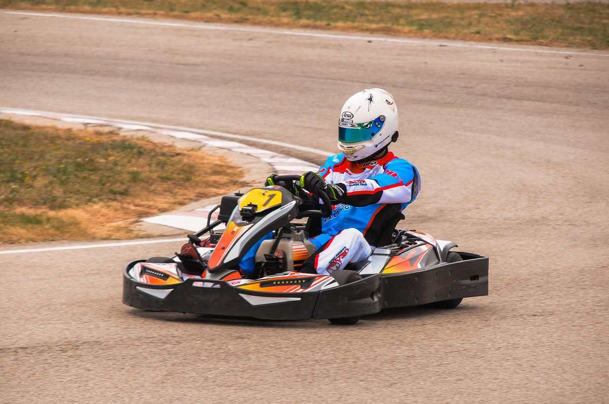 Un pilote en karting, casque bleu, manœuvre son kart sur piste Un pilote en karting, casque bleu, manœuvre son kart sur piste