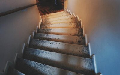 Des marches usées et une rampe dans un couloir sombre