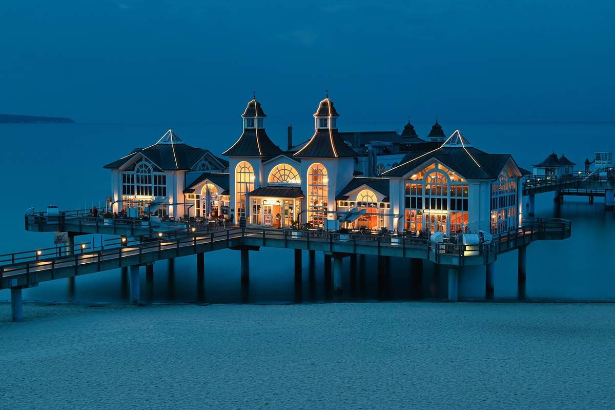 Un bâtiment lumineux sur un pont flottant au bord de la mer
