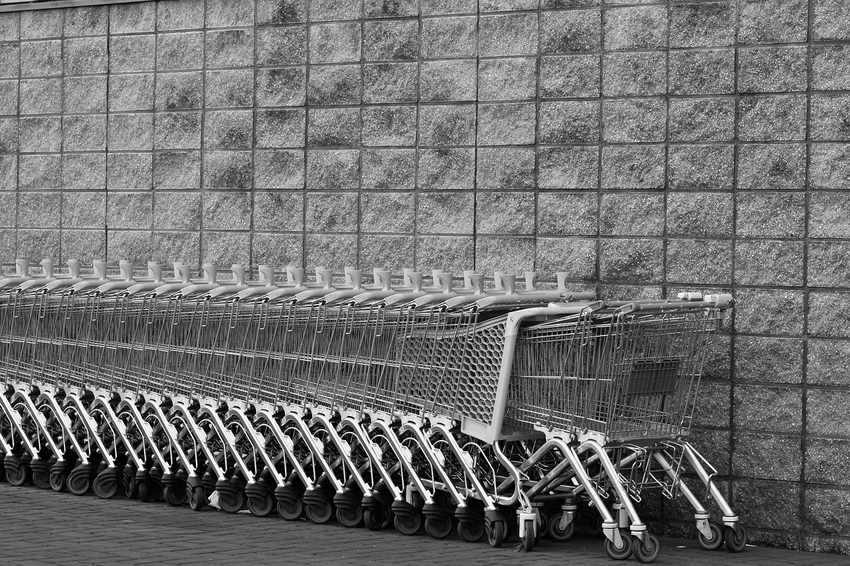 Rangée de chariots de supermarché métalliques alignés le long d'un mur en béton Rangée de chariots de supermarché métalliques alignés le long d'un mur en béton