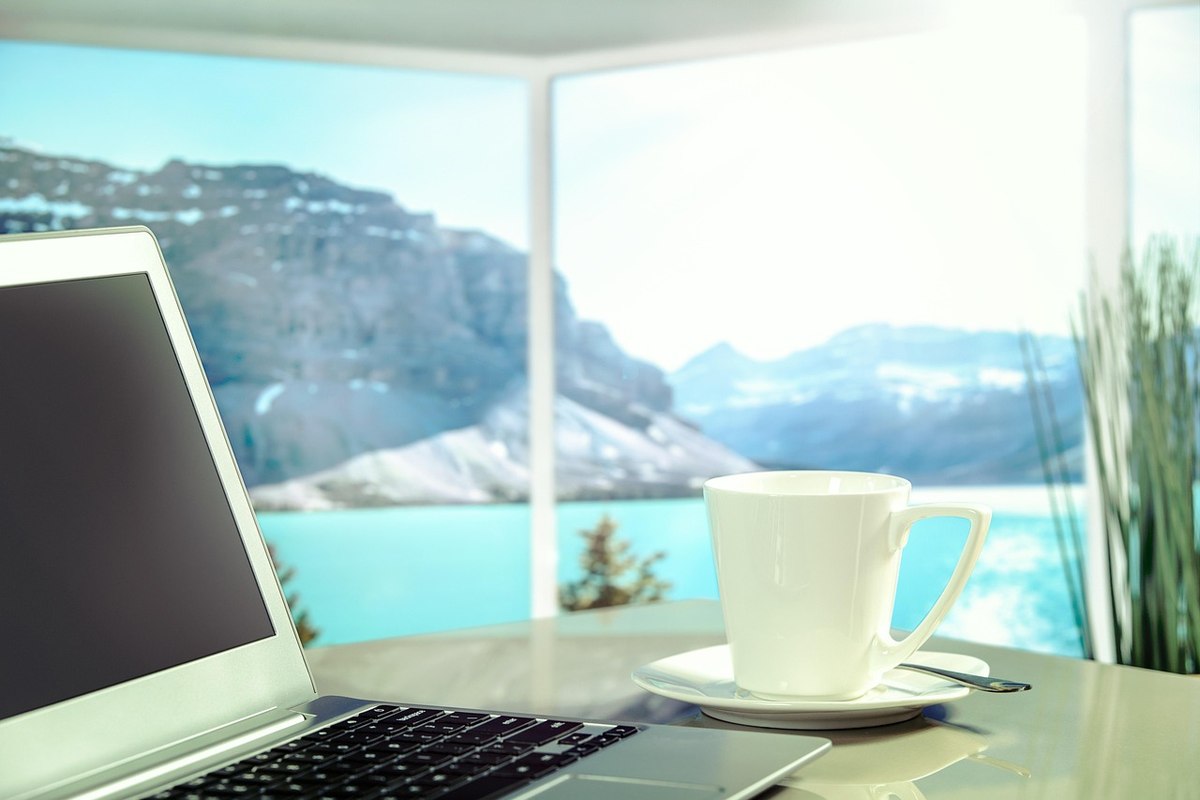 Ordinateur, tasse de café, table, vue sur lac et montagnes
