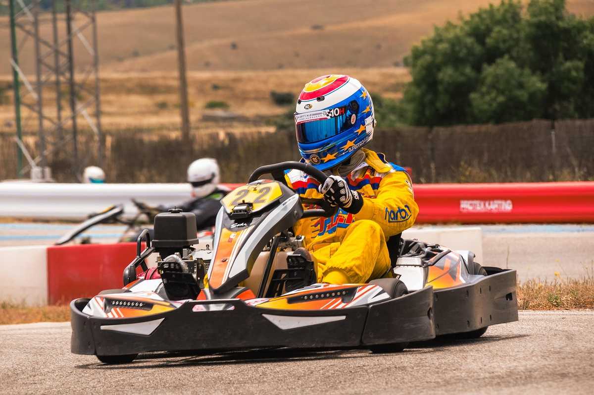 Un pilote en kart jaune et casque coloré conduit sur un circuit Un pilote en kart jaune et casque coloré conduit sur un circuit