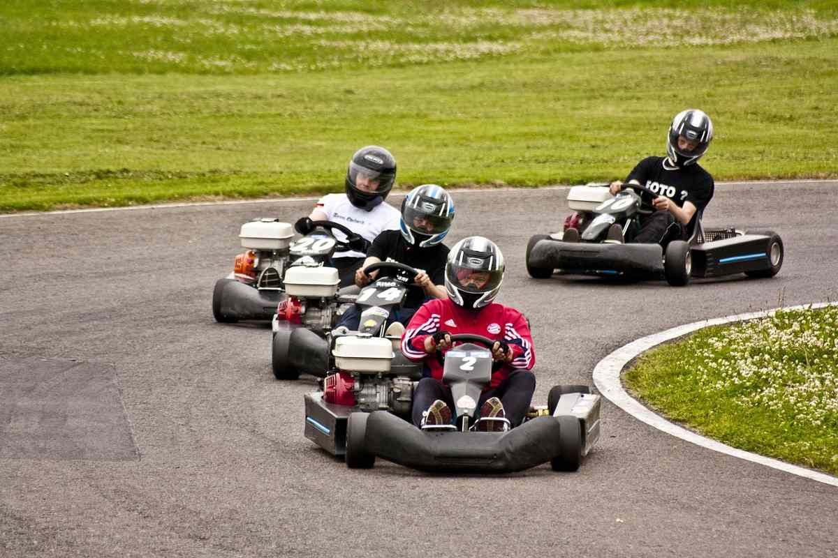 Quatre conducteurs en casque pilotent des karting sur une piste courbe