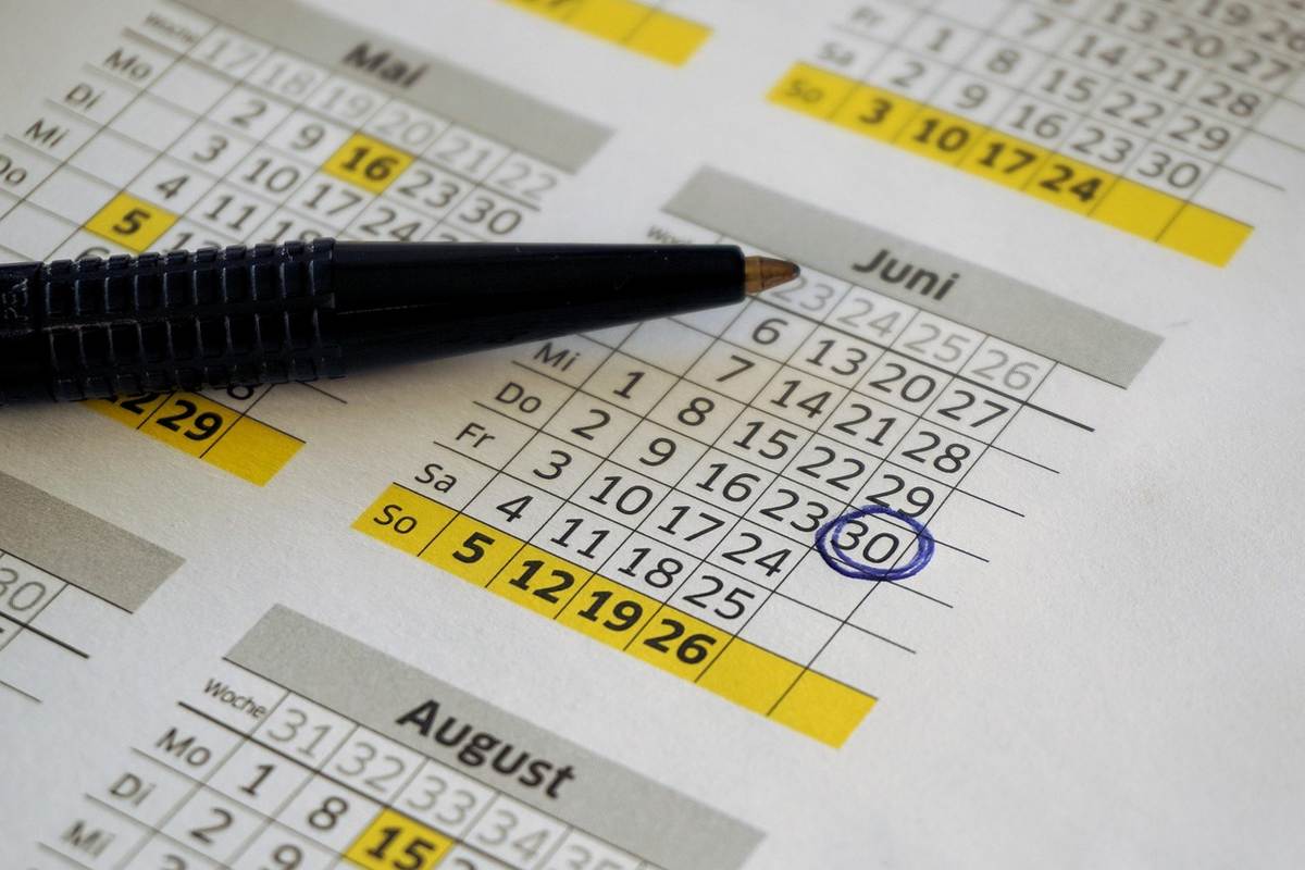 Un stylo pointe le 30 juin sur un calendrier affiché