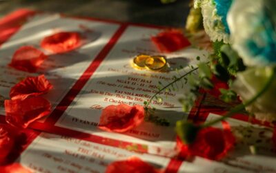 Cartes d'invitation, alliances d'or, pétales de rose et fleurs sous lumière