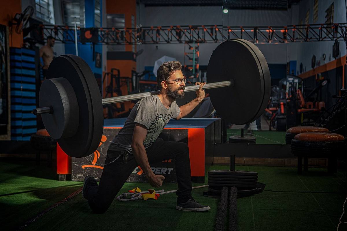 Homme musclé en squat avec barre chargée dans une salle de musculation